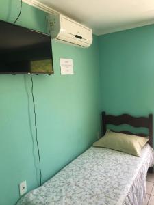 a bedroom with a bed and a flat screen tv at Pousadajn in Florianópolis +12 photos