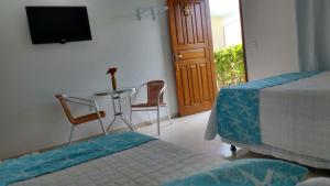 1 dormitorio con 1 cama, mesa y sillas en Pousada Bela Pinheira, en Palhoça