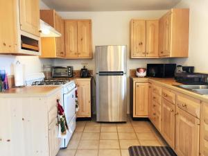 cocina con armarios de madera y nevera de acero inoxidable en 29 Hillside by JTNP Visitor Center, en Twentynine Palms
