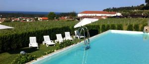 a swimming pool with chairs and umbrellas next to a field at Quinta do Paco d'Anha in Viana do Castelo