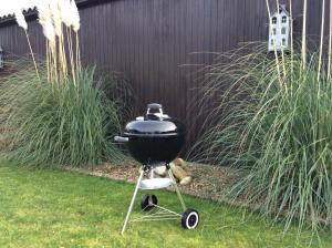 a charcoal grill on a stand in a garden at Bungalow kleine Deichperle, Strand, Deich und ein wunderschöner kleiner Ort in unmittelbarer, fußläufger Nähe! in Lemmer
