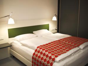 a bed with a red and white checkered blanket on it at DASKöln in Cologne