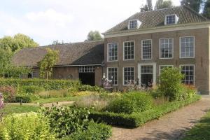 une grande maison en briques avec un jardin en face de celle-ci dans l'établissement COSY & NATURAL *FIREPLACE*GARDEN*2 BIKES, à Heinenoord