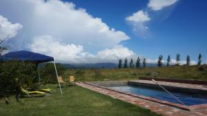 una piscina con sillas y una sombrilla en un patio en Los Chañaritos, en La Cumbre
