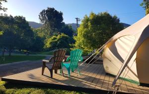 Jamieson的住宿－Jamieson Caravan Park，两把椅子坐在帐篷旁边的甲板上
