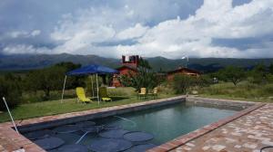una piscina con dos sillas y una sombrilla en Los Chañaritos, en La Cumbre