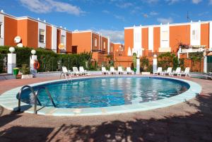 a swimming pool in a courtyard with chairs and buildings at Cielo Azul in La Tejita