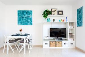 a white living room with a tv and a table at Cielo Azul in La Tejita