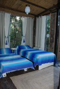 two beds in a bedroom with blue sheets at La Escondida in Punta del Este