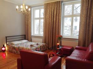 a bedroom with a bed and a couch and windows at Stylowa Kamienica w Centrum in Olsztyn