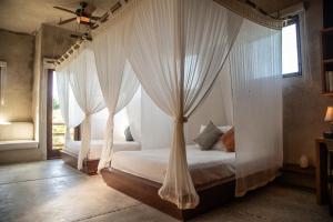 a bedroom with a canopy bed with white drapes at Casa Maya Kaan in Tulum