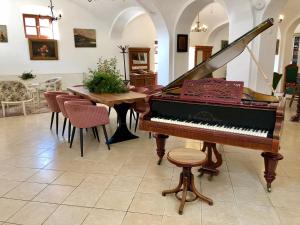 a piano in a room with a table and chairs at The Houses of History - anno 1830 in Tihany