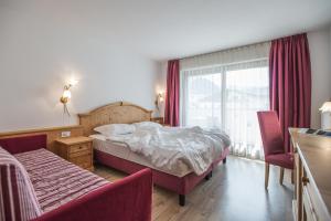 una camera da letto con un letto, una sedia e una finestra di Hotel Innerhofer a Gais