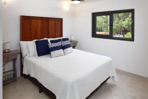 Un dormitorio con una cama blanca con almohadas azules y blancas en Villa Robalo B - Villas del Palmar, en Sayulita
