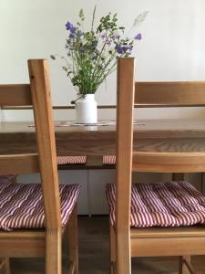 a wooden chair with a table with a vase of flowers at Chaty Pohoda na Soláni in Velké Karlovice