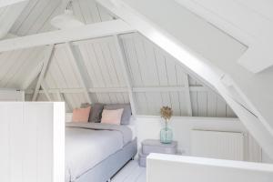 a bedroom with a bed in a white attic at De Friese Wouden in Suameer