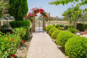 a garden with a gate and pink flowers and bushes at Paul's Garden Studios in Haraki