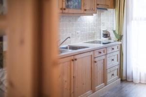 a kitchen with wooden cabinets and a sink at Appartement & Hotel Innerhofer in Gais