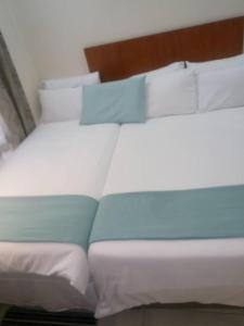 Una cama con almohadas blancas y azules. en Eros Guest Inn en Francistown
