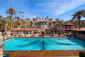 a large pool in front of a house with palm trees at The Inn at Death Valley in Indian Village