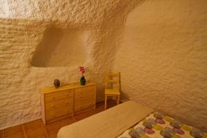 een slaapkamer met een bed, een dressoir en een stoel bij Cueva Pura Vida in Pulpite +37 foto's