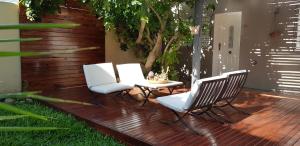 3 sillas y una mesa en una terraza de madera en Antigua Fonda Hosteria en Concepción del Uruguay