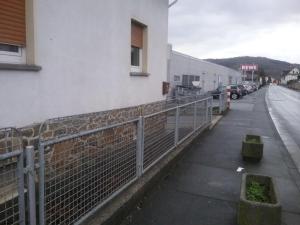 a fence on the side of a building next to a street at Pension Ehringshausen in Ehringshausen