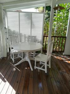 un tavolo bianco e sedie su un portico di la case dentelle bungalow a Le Diamant