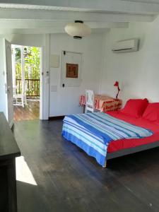 a bedroom with a large bed with red and blue sheets at la case dentelle bungalow in Le Diamant