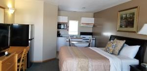 a small bedroom with a bed and a kitchen at Athabasca Lodge Motel in Athabasca