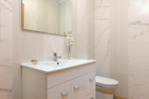 a white bathroom with a sink and a toilet at Vivenda Golfinho Barra in Praia da Barra +2 photos