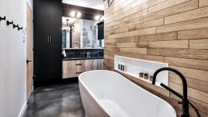 e bagno con vasca e parete in legno. di Le Saint-Laurent - Résidences Boutique a Petite-Rivière-Saint-François