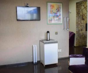 a room with a refrigerator and a tv on the wall at Diplomata Hotel in Sertãozinho