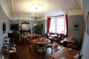 a dining room with tables and chairs and a chandelier at Rolling Wave Guesthouse in Bundoran