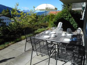 - une table avec des chaises et un parasol sur la terrasse dans l'établissement Casa Pignia, à Laax