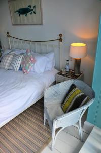 a bedroom with a bed and a chair and a lamp at Lulworth Cove Inn in Lulworth Cove