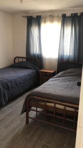 a bedroom with two beds and a window with blue curtains at Casa El Quisco in El Quisco