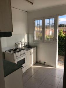 a white kitchen with a stove and a window at Casa El Quisco in El Quisco