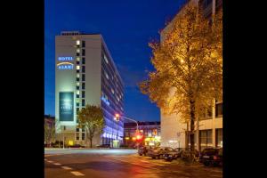 una strada di città di notte con un palazzo alto di Hotel Asahi a Dusseldorf