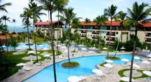 um resort com piscina, cadeiras e palmeiras em Flats Marulhos Resort by BMS em Porto de Galinhas