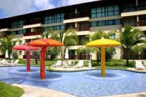 uma piscina com guarda-sóis em frente a um edifício em Flats Marulhos Resort by BMS em Porto de Galinhas