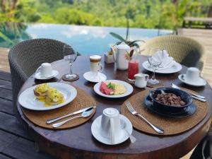 a wooden table with plates of food on it at Kamaniiya River Villa Sayan - Ubud in Ubud