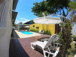 a patio with two chairs and an umbrella and a pool at Pousada Kai in Itanhaém