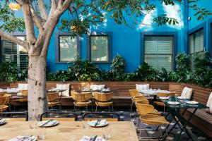 a restaurant with tables and chairs in front of a blue wall at Palihotel Culver City in Los Angeles
