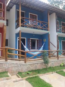 a blue and white house with a hammock on the porch at Apartamento 05 Vivendas do Serrano - Lençóis in Lençóis