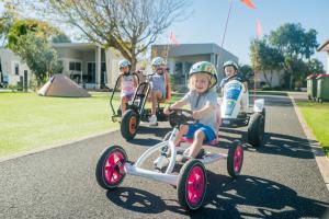 een groep kinderen op driewielers in een straat bij BIG4 Ingenia Holidays Queenscliff Beacon in Queenscliff