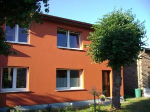 una casa arancione con un albero di fronte di Ferienwohnungen Kanuhof a Freest