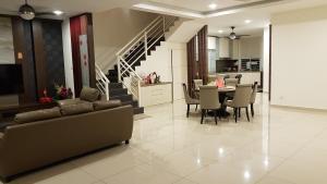 uma sala de estar com um sofá e uma mesa com cadeiras em Malacca Homestay - 2 Storey Semi-D em Malaca