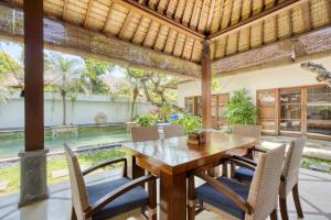 an outdoor dining room with a wooden table and chairs at VILLA AISHA in Sanur