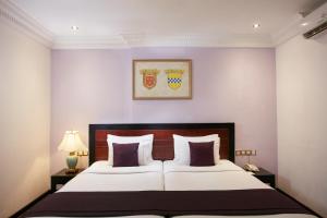 1 dormitorio con 1 cama blanca grande con almohadas moradas en The Steuart by Citrus en Colombo